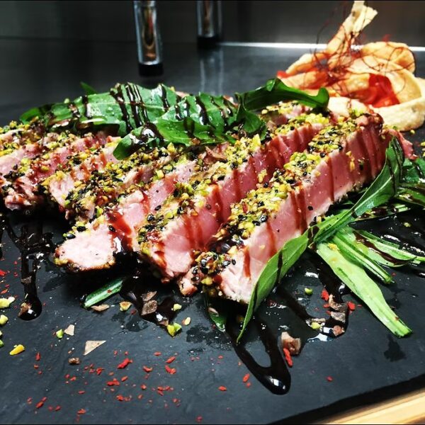 Tagliata di tonno pinna gialla servita con pomodorini, grana e rucola